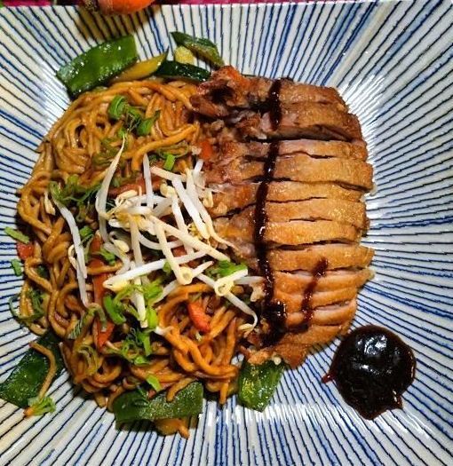Ein Teller mit Fleisch und Gemüse auf einem Tisch. Samt Asia Kitchen GmbH
