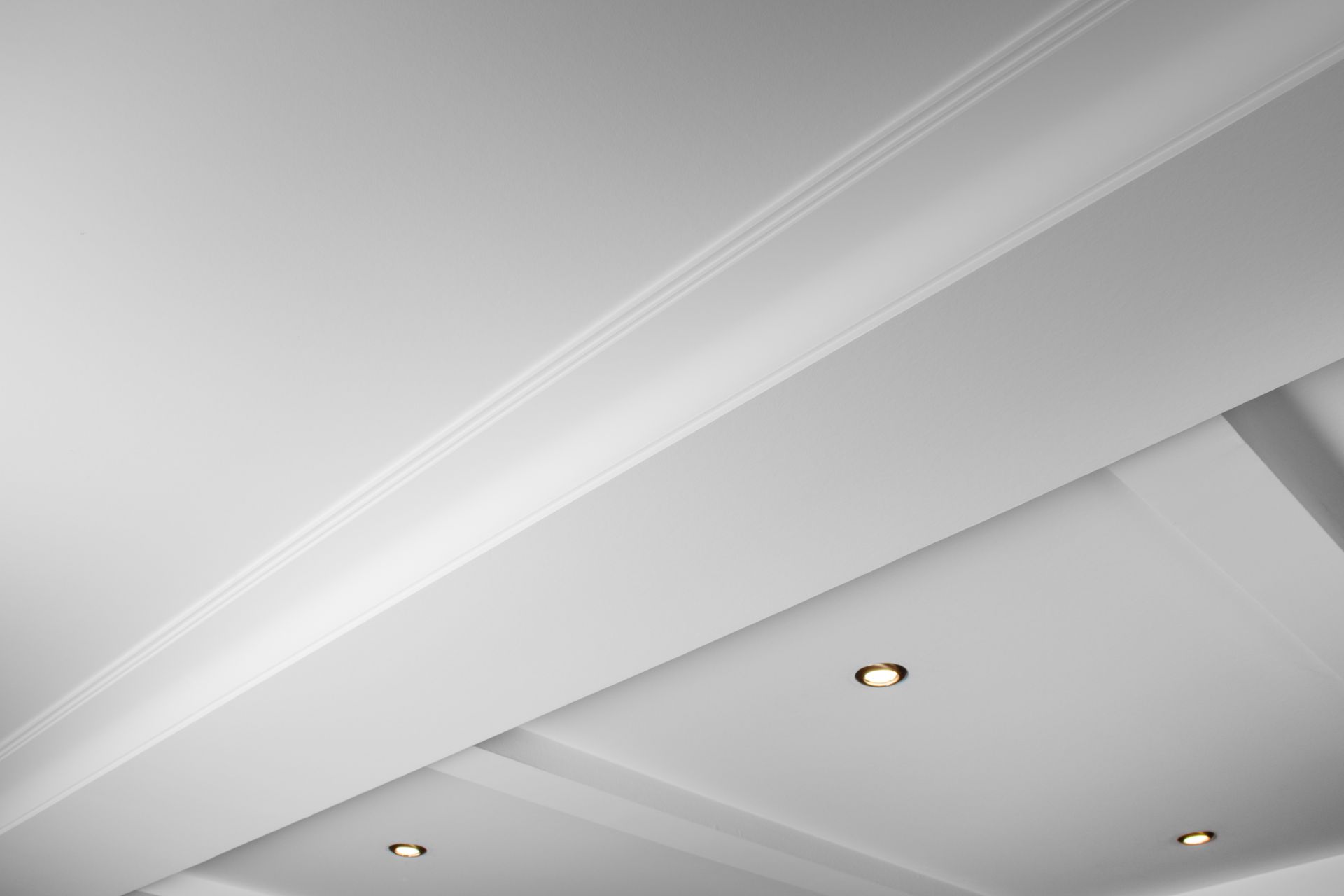 Plafond blanc avec moulures et spots encastrés.