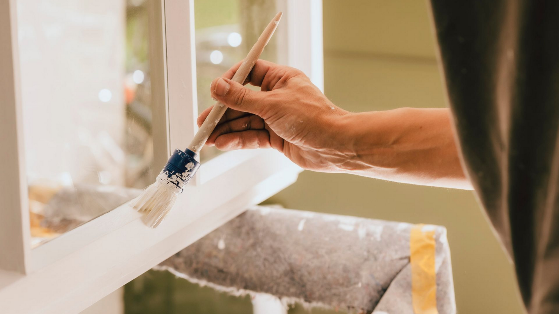 Peinture d'un cadre de fenêtre blanc au pinceau.
