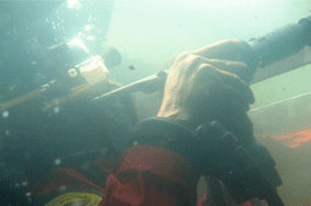 La mano enguantada de un buceador agarra una barra bajo el agua, parte de lo que parece ser una operación de rescate.