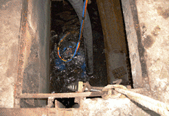 Agujero abierto y oscuro con cables y escombros en su interior, visto desde arriba.