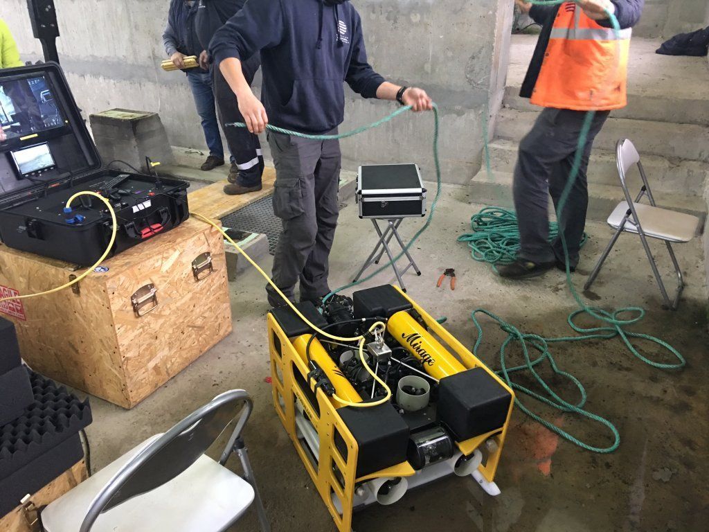 Personas preparando un sumergible amarillo con equipo de control conectado, probablemente para trabajos submarinos.