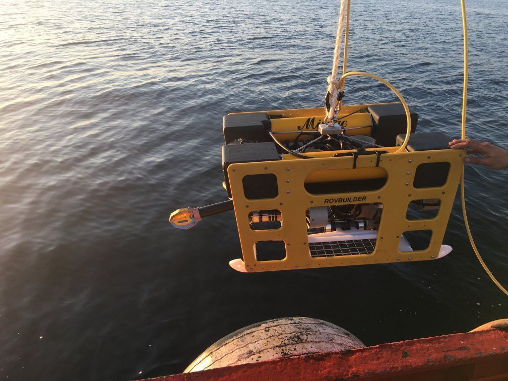 Dron submarino amarillo siendo bajado al océano desde un barco.