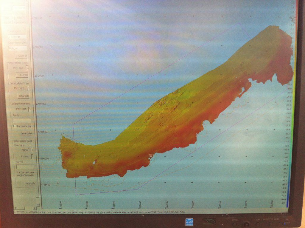 Pantalla de computadora que muestra un escaneo submarino alargado y colorido que muestra diferentes profundidades, probablemente del fondo marino.