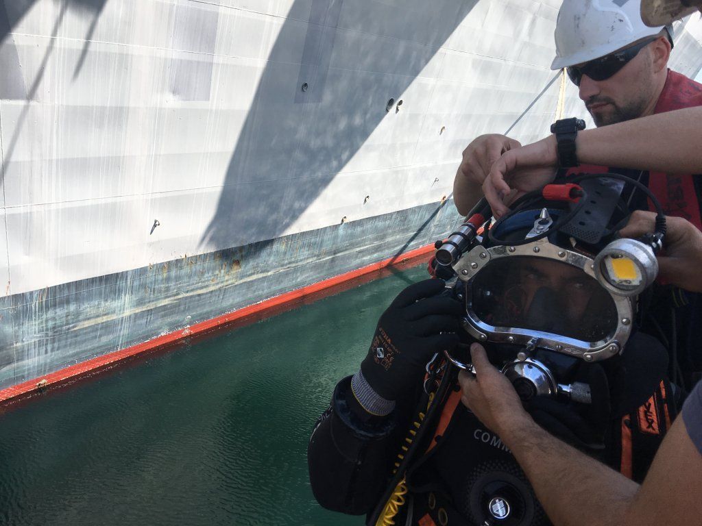 Buceador recibe asistencia de un barco antes de sumergirse. Lleva equipo de buceo.
