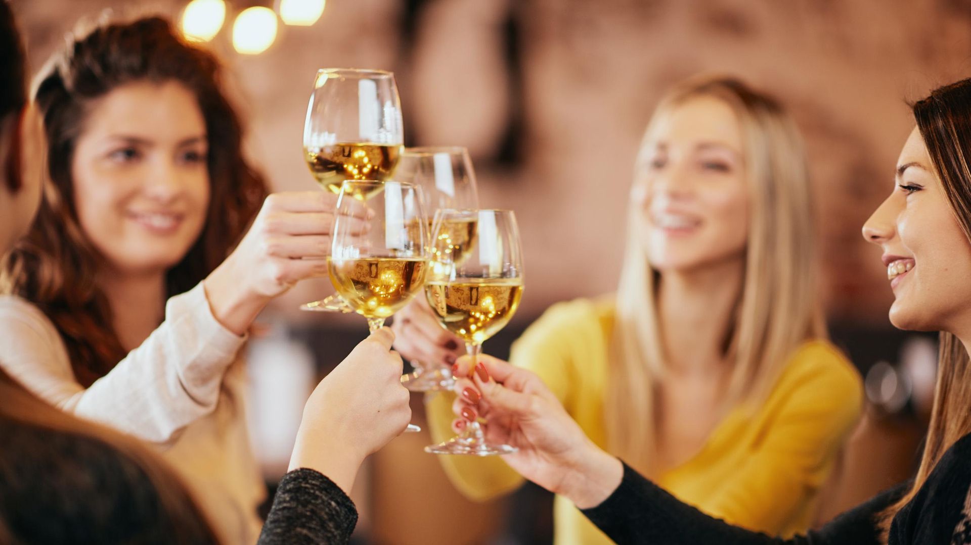 Freunde stoßen bei einem gemütlichen, sanft beleuchteten Treffen mit Weingläsern an.