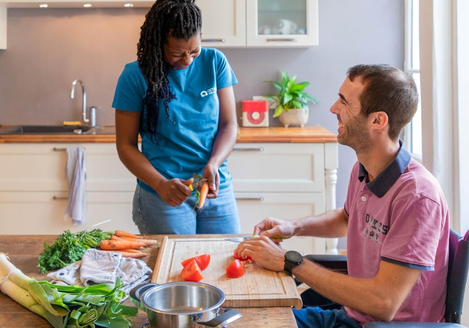 Deux personnes préparent ensemble à manger dans une cuisine lumineuse, avec des légumes et un saladier sur le plan de travail