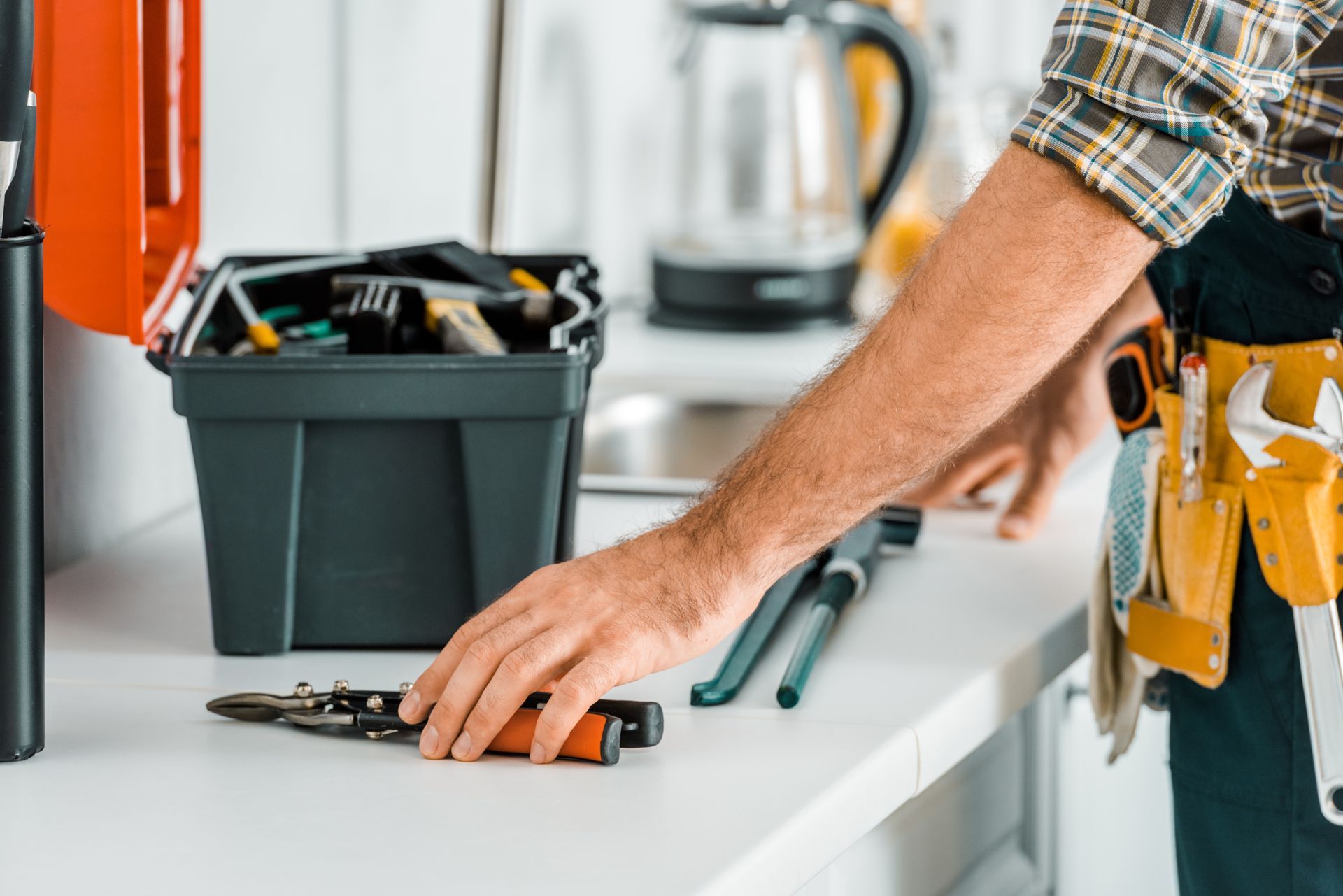 Un bricoleur, muni d'outils et d'une boîte à outils, en train de mesurer et de réparer un tiroir