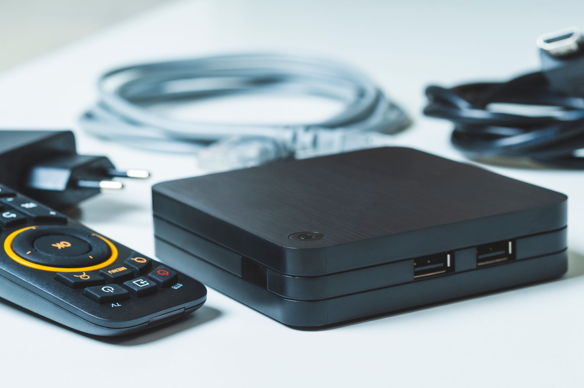 Boîtier multimédia noir avec télécommande, câble USB et adaptateur secteur sur une surface blanche