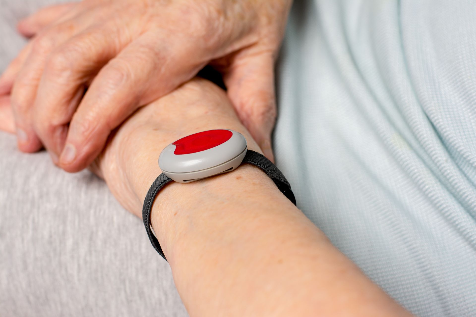 Personne âgée portant un dispositif de téléassistance autour du poignet avec les mains croisées