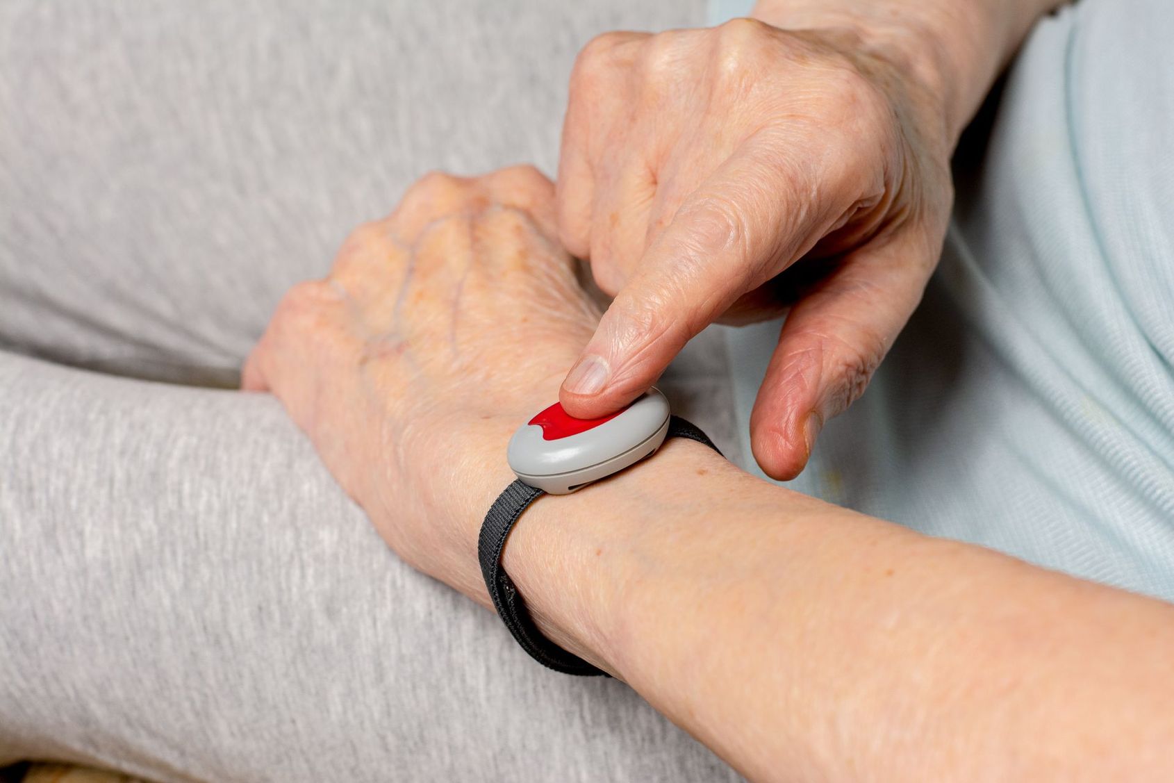Personne appuyant sur un bouton rouge d'un dispositif d'alerte fixé au poignet