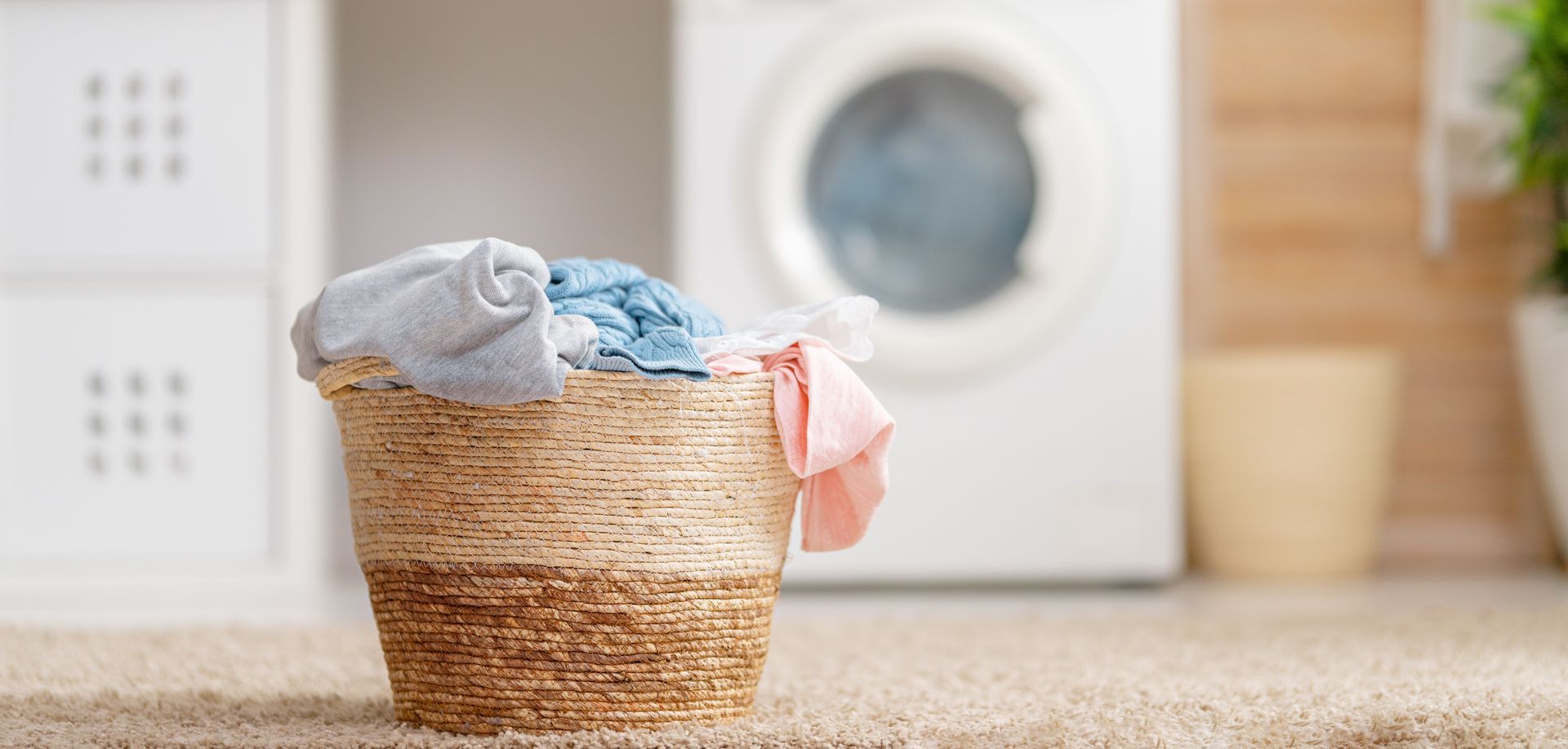 Panier à linge rempli de vêtements devant une machine à laver