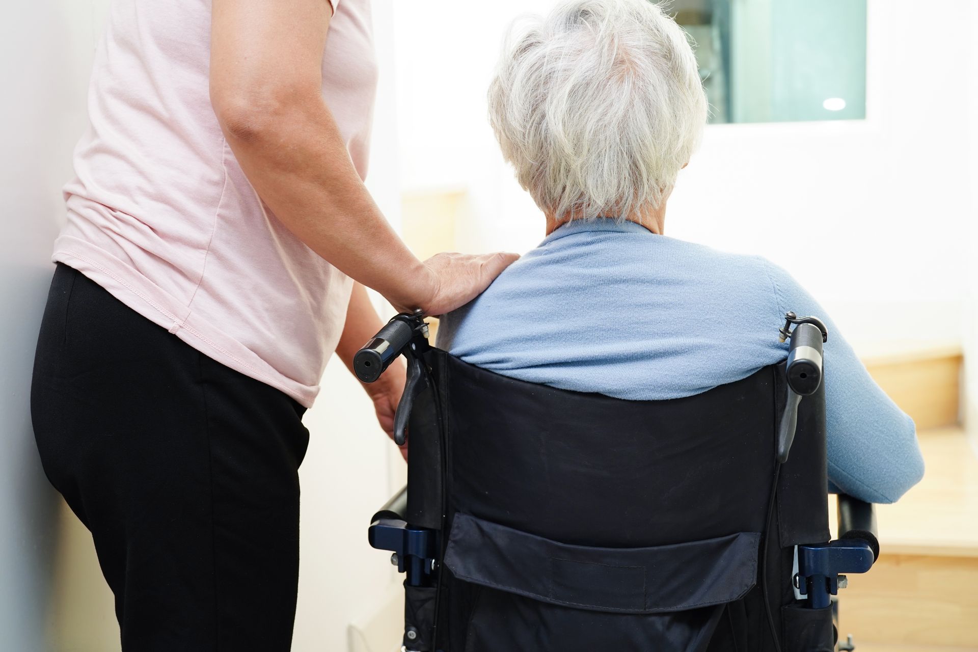 Personne aidant une personne assise dans un fauteuil roulant à l'intérieur