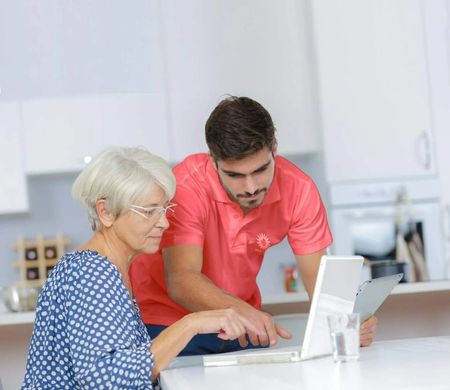 Un homme et une femme âgée travaillent ensemble sur un ordinateur portable dans un bureau