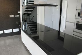 Una cocina con encimera negra y una escalera al fondo.