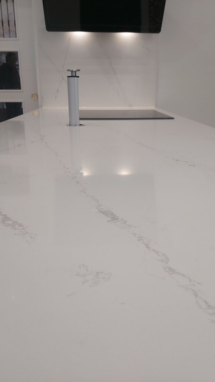 Una encimera blanca con un grifo en una cocina.