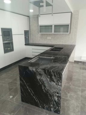 Una cocina con encimera de granito negro y gabinetes blancos.