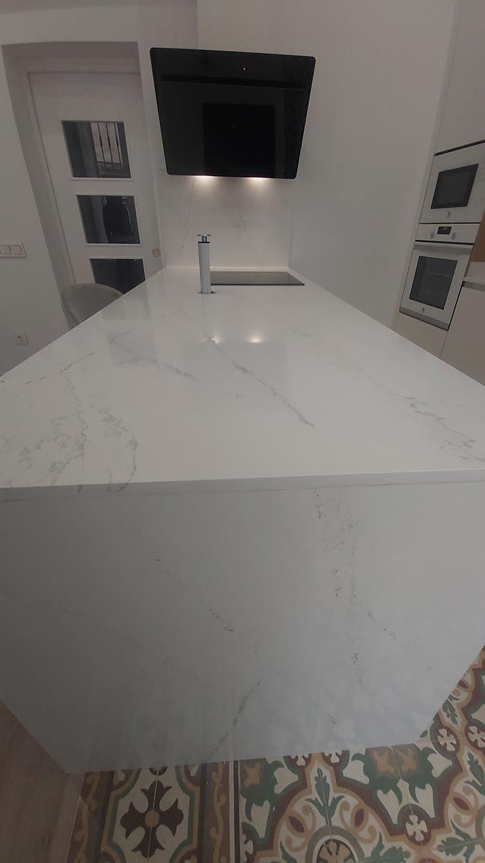 Una cocina con una gran encimera blanca y una campana extractora negra.