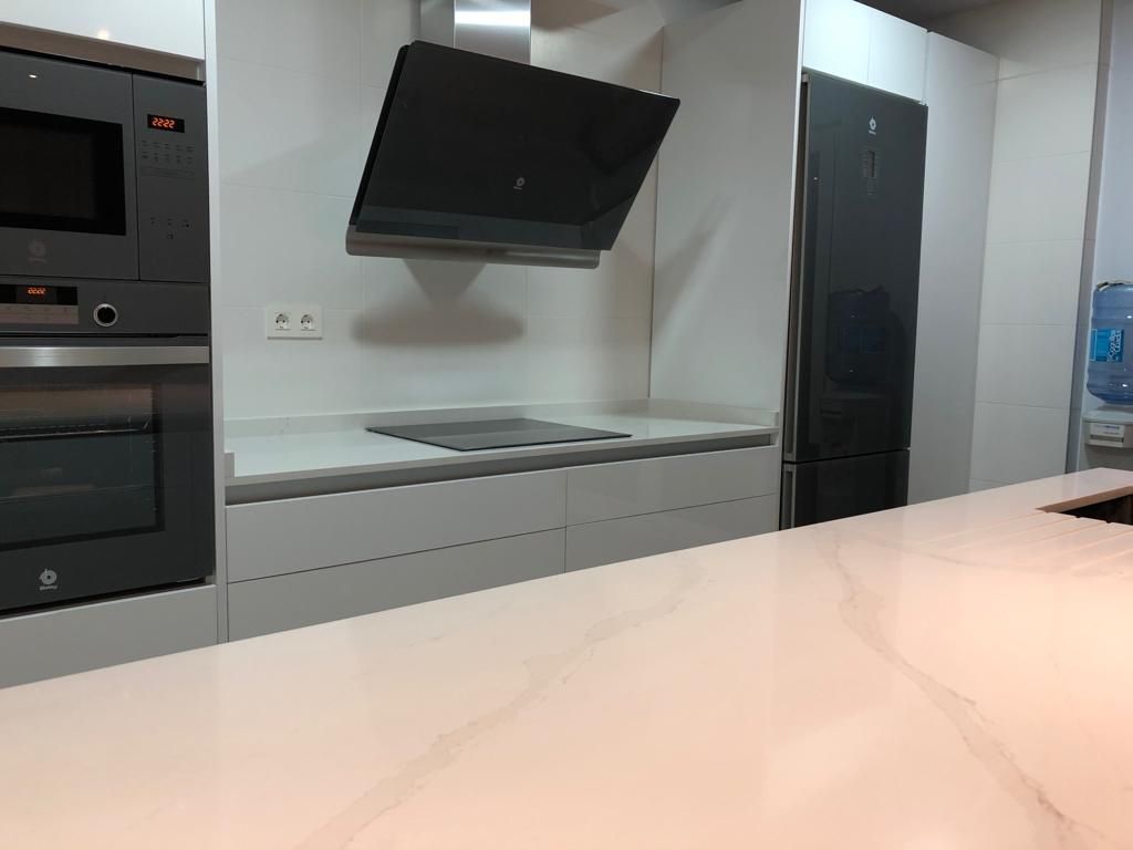 Una cocina con estufa, horno, refrigerador y microondas.