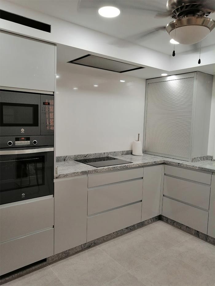 Una cocina con gabinetes blancos y un ventilador de techo.