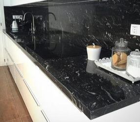 Una cocina con encimera de granito negro y gabinetes blancos.