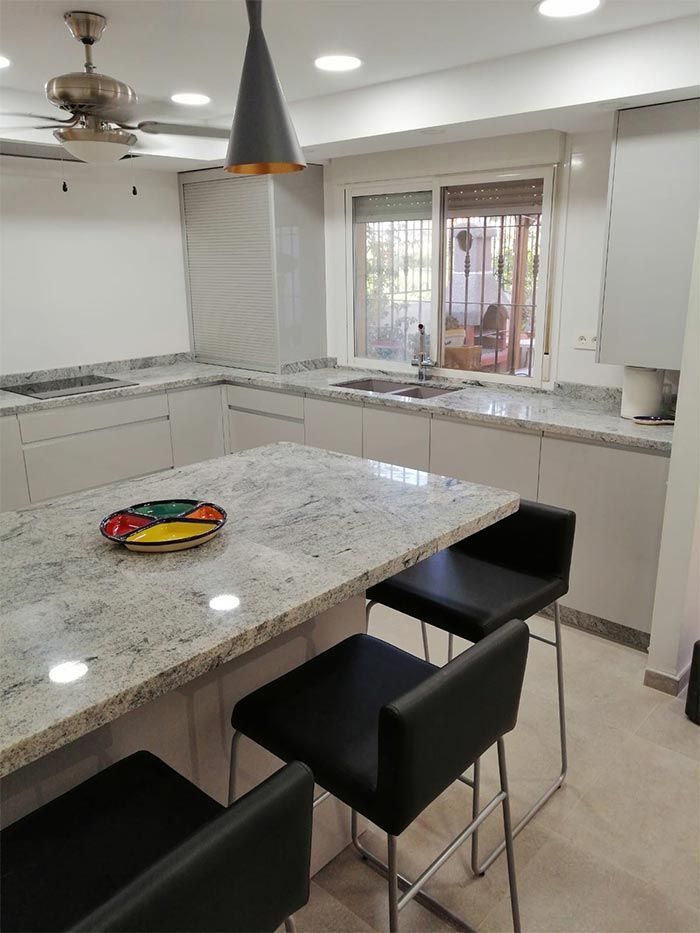 Una cocina con encimeras de granito y sillas negras.