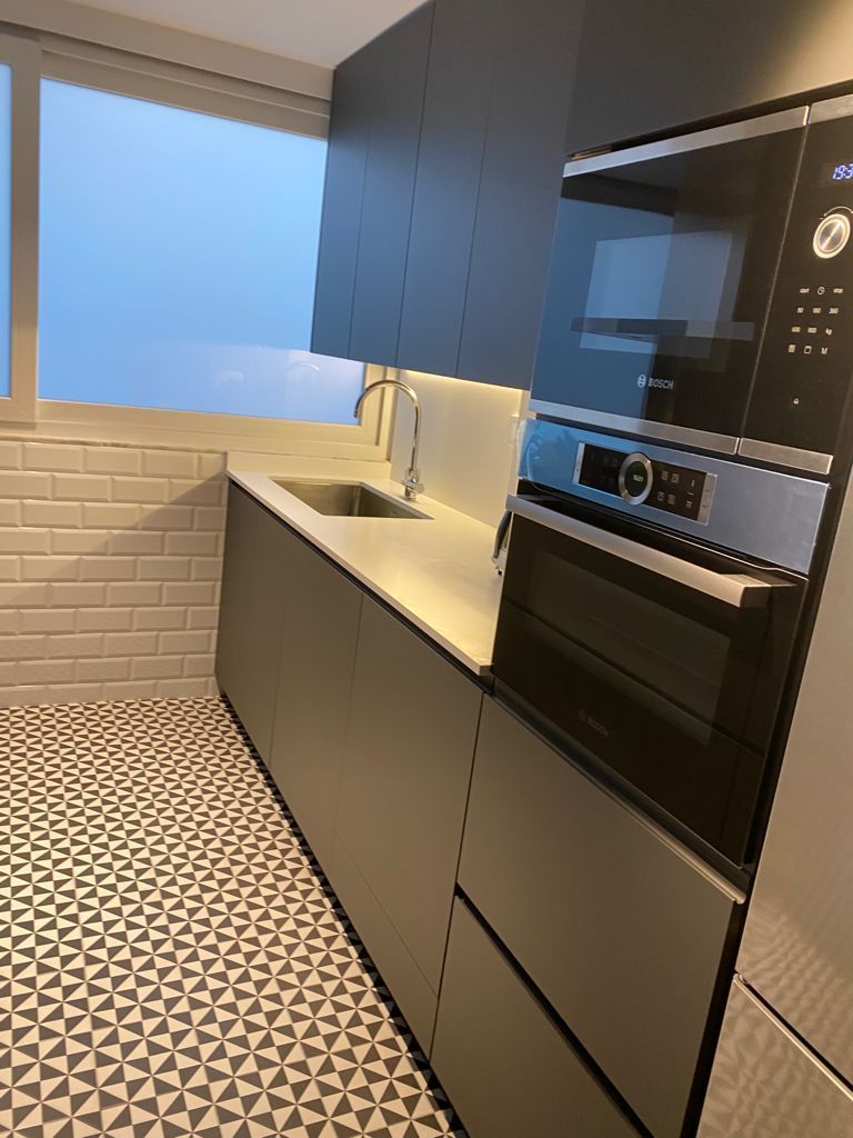 Una cocina con fregadero, horno, microondas y ventana.