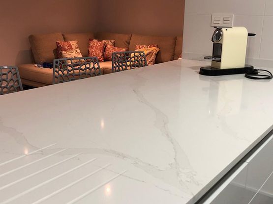 Un mostrador de cocina con una cafetera y un sofá al fondo.