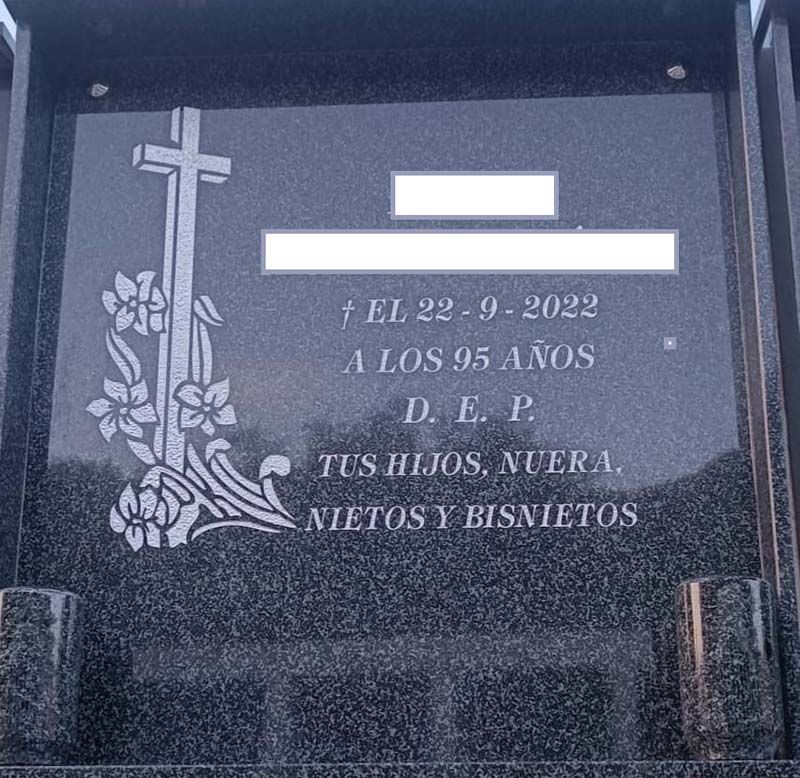 Una lápida con una cruz y flores.