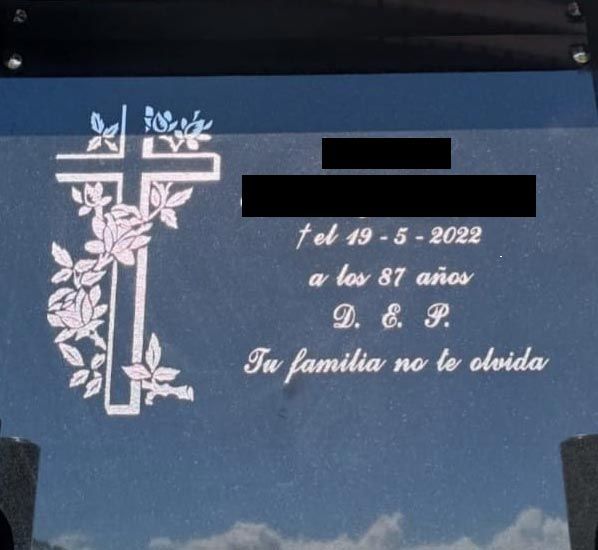Una placa con una cruz y flores dice 