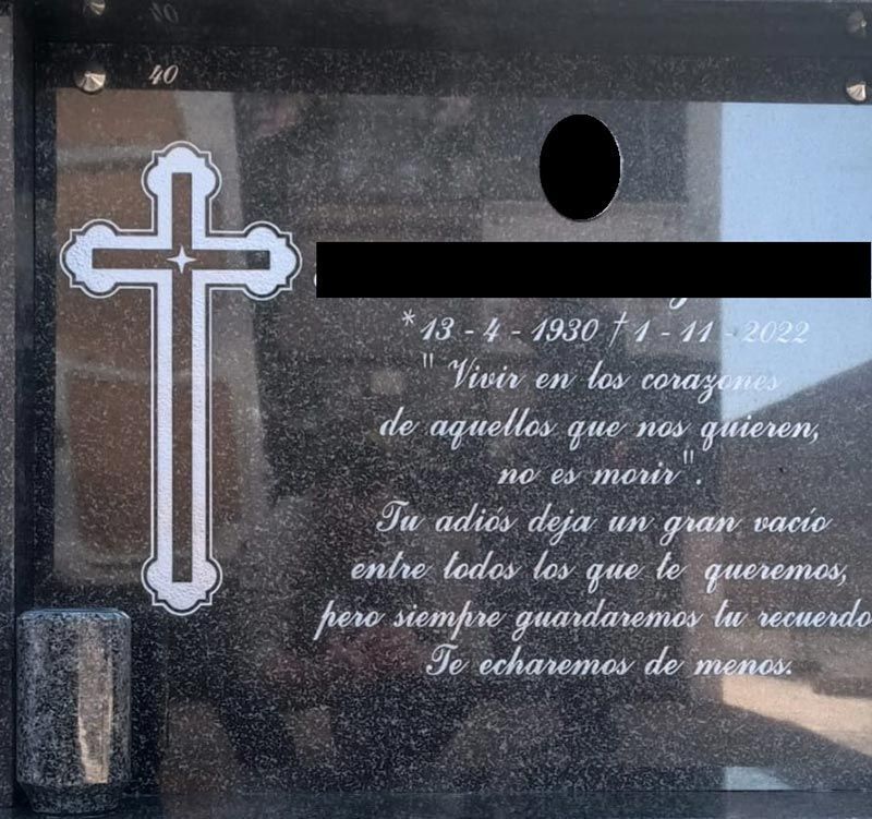 Una lápida con una cruz y una cita en español.