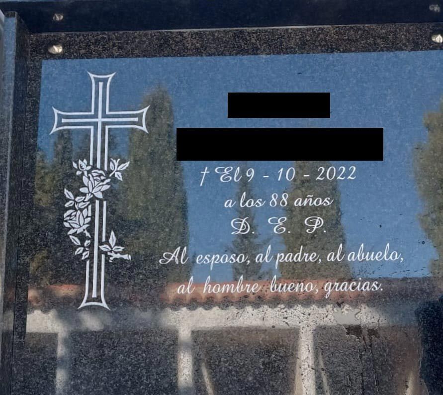 Una lápida con una cruz y flores.