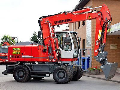 Ein roter Liebherr-Radbagger mit angehobener Schaufel steht neben einem Gebäude.