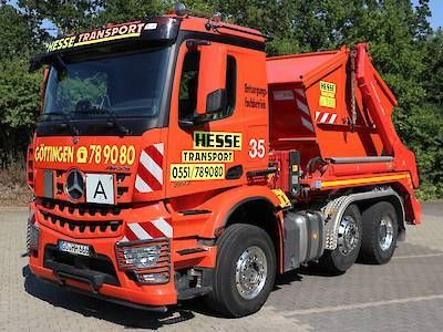 Orangefarbener Muldenkipper von Hesse Transport parkt auf der Straße, Seitenansicht