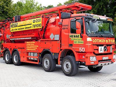 Ein roter Abschleppwagen der Marke Hesse mit Kran steht im Freien auf einem gepflasterten Parkplatz.
