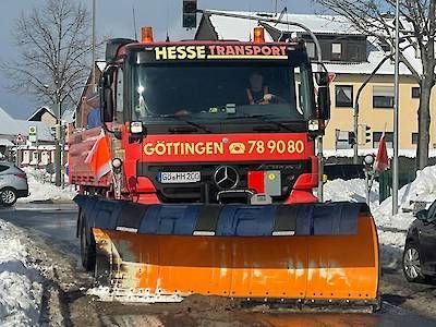 Ein roter Schneepflug räumt eine verschneite Straße in Göttingen.