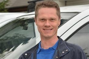 Ein Mann in einem blauen Hemd steht vor einem weißen Lieferwagen. Karl-Heinz Müller GmbH