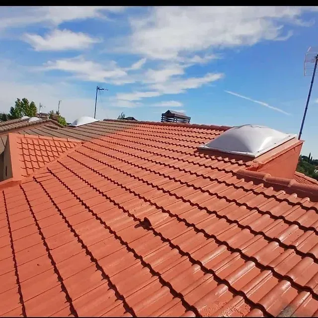 Un techo de tejas rojas con un tragaluz encima
