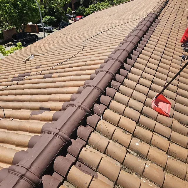 Un techo con tejas marrones y una pala roja encima.