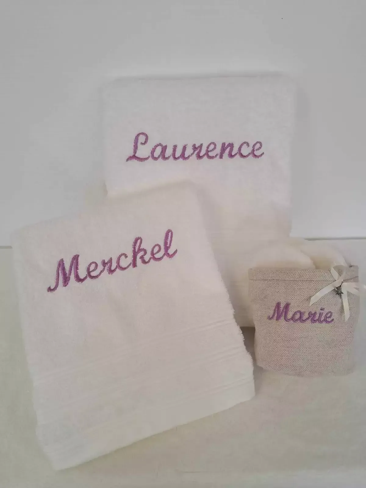 Tissus blancs brodés avec les noms Laurence, Merckel et Marie en violet
