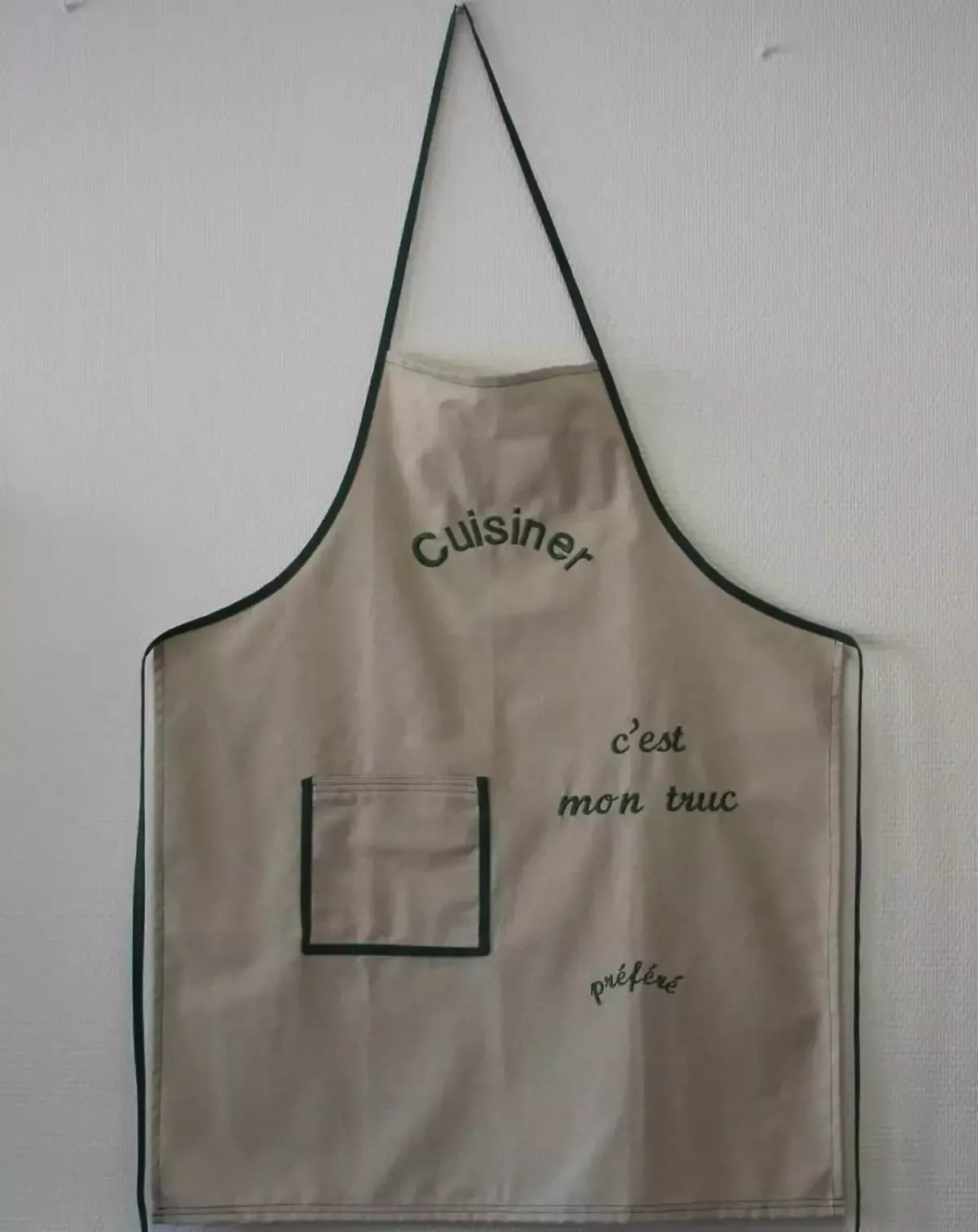 Tablier accroché au mur avec inscription en français et petite poche