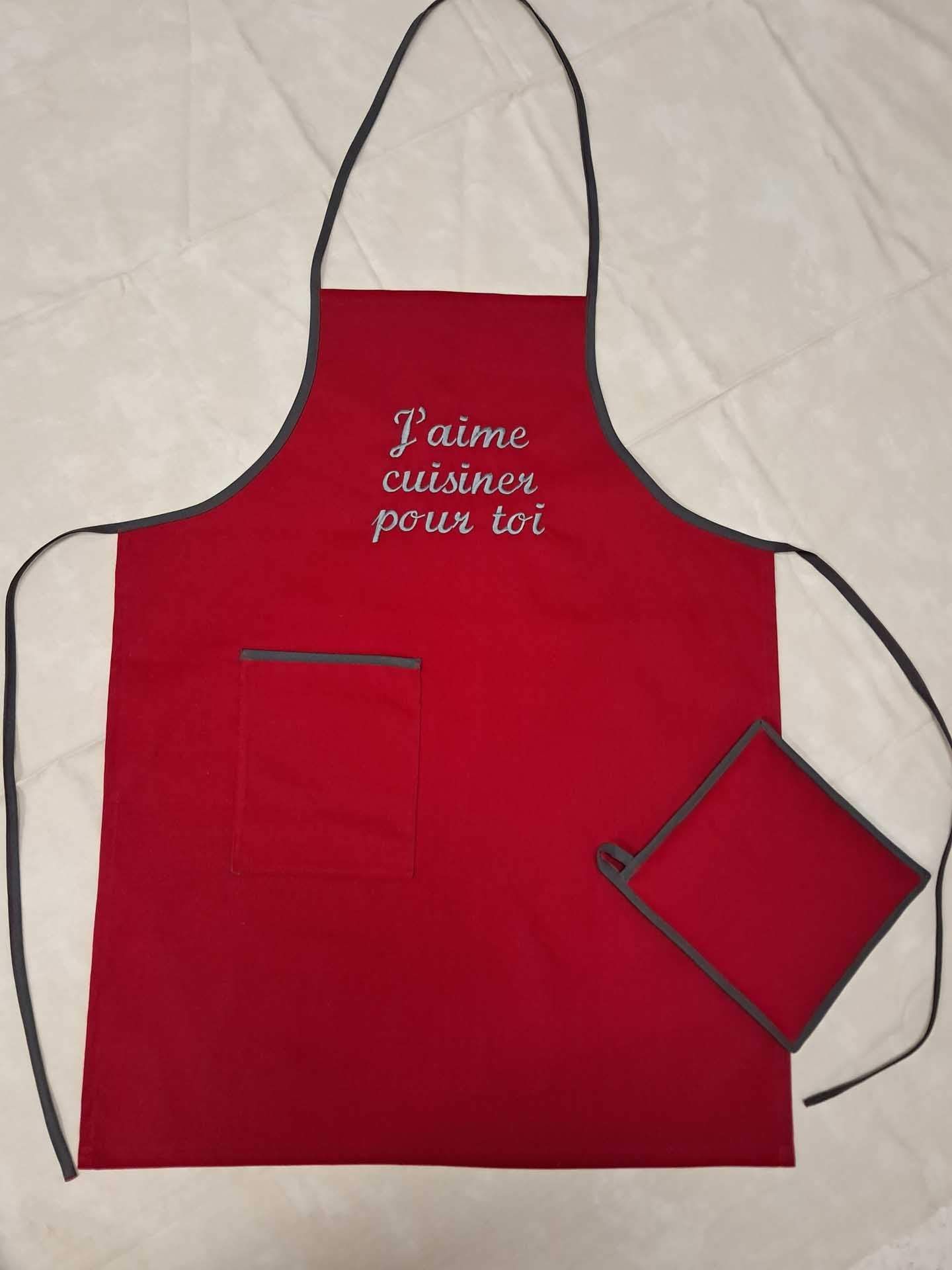 Tablier rouge avec inscription française blanche et petite manique assortie sur fond de tissu clair