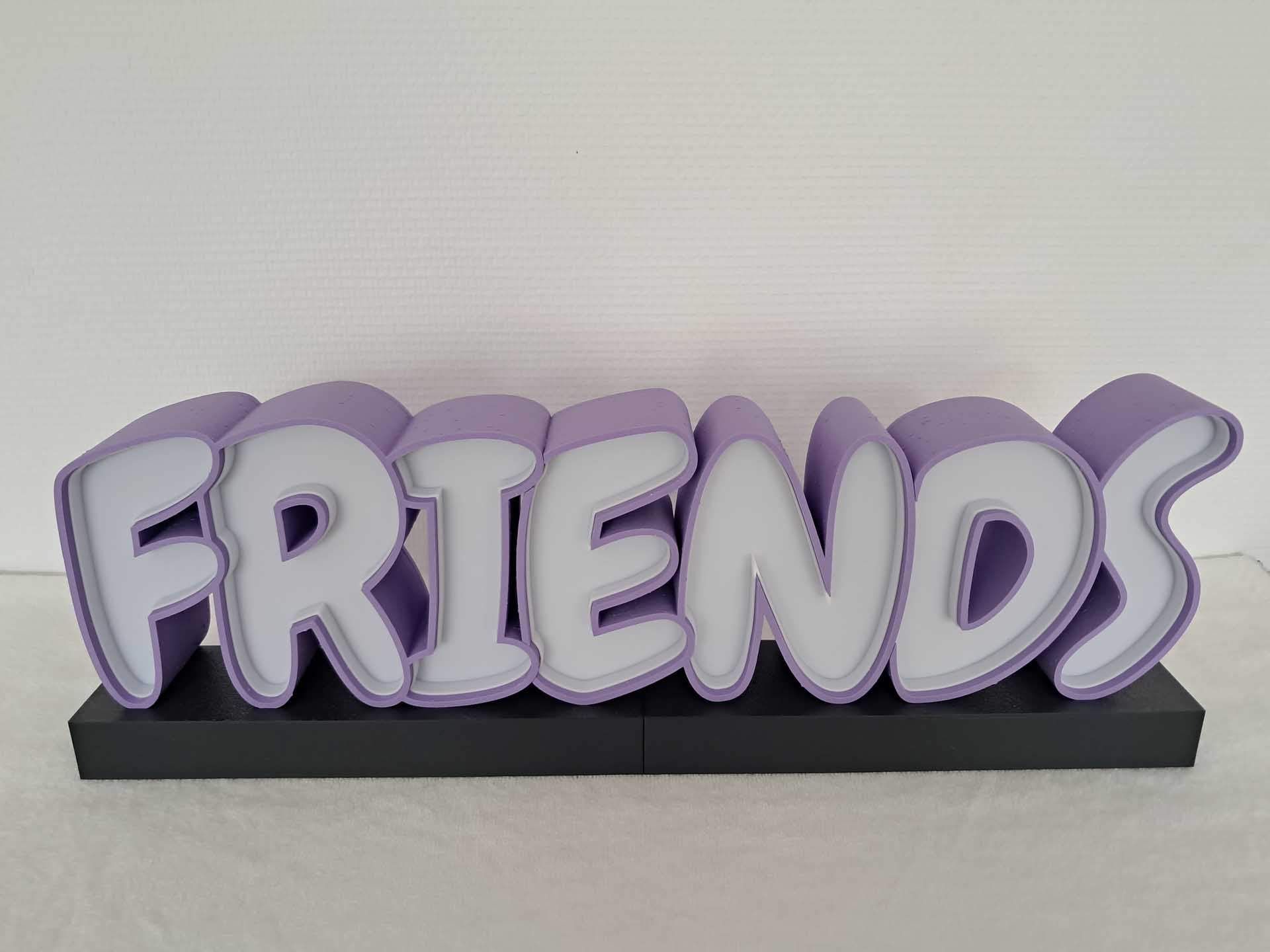 Panneau « FRIENDS » violet en 3D sur fond noir et clair.