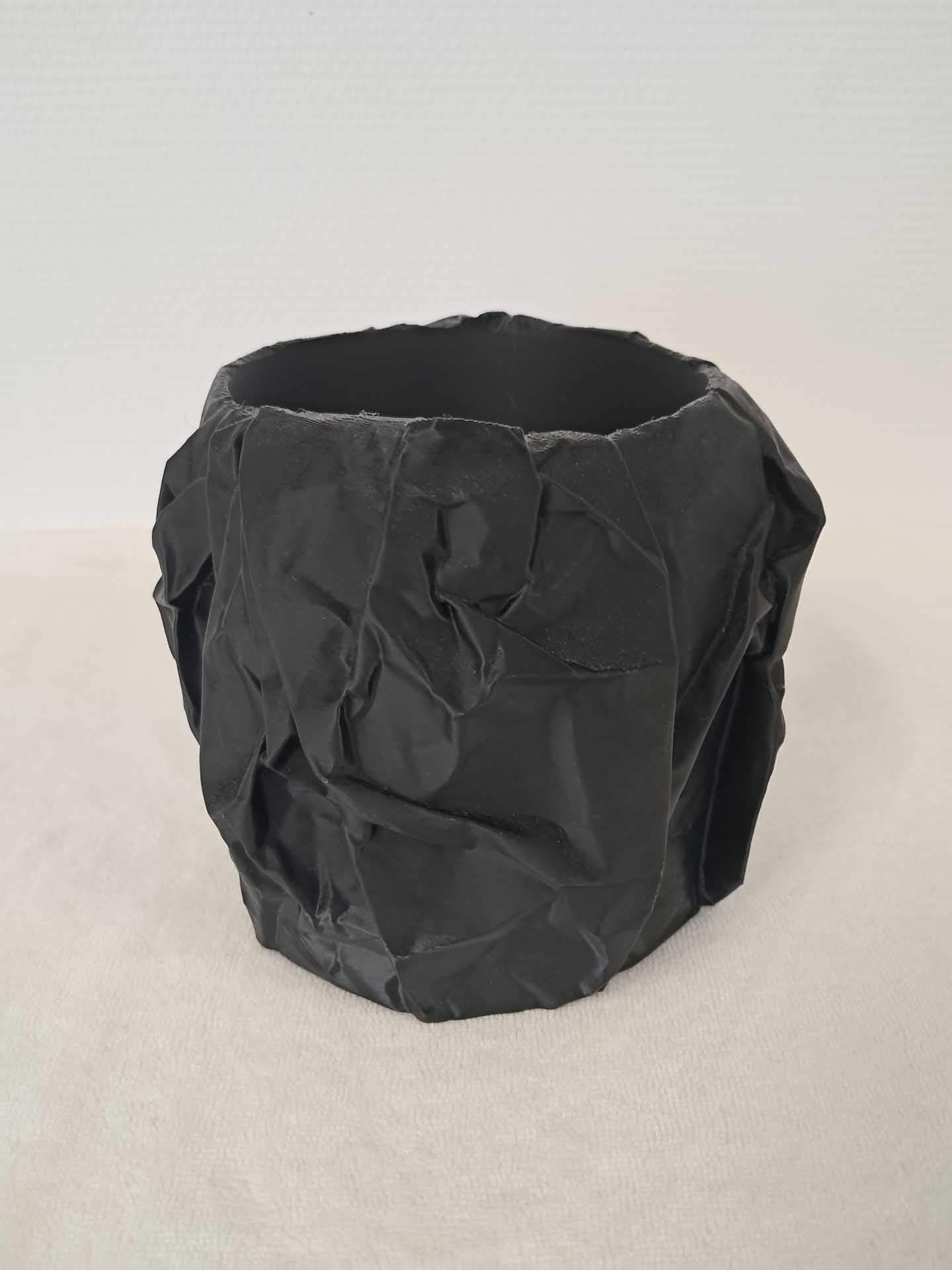 Gobelet en papier noir froissé sur fond clair