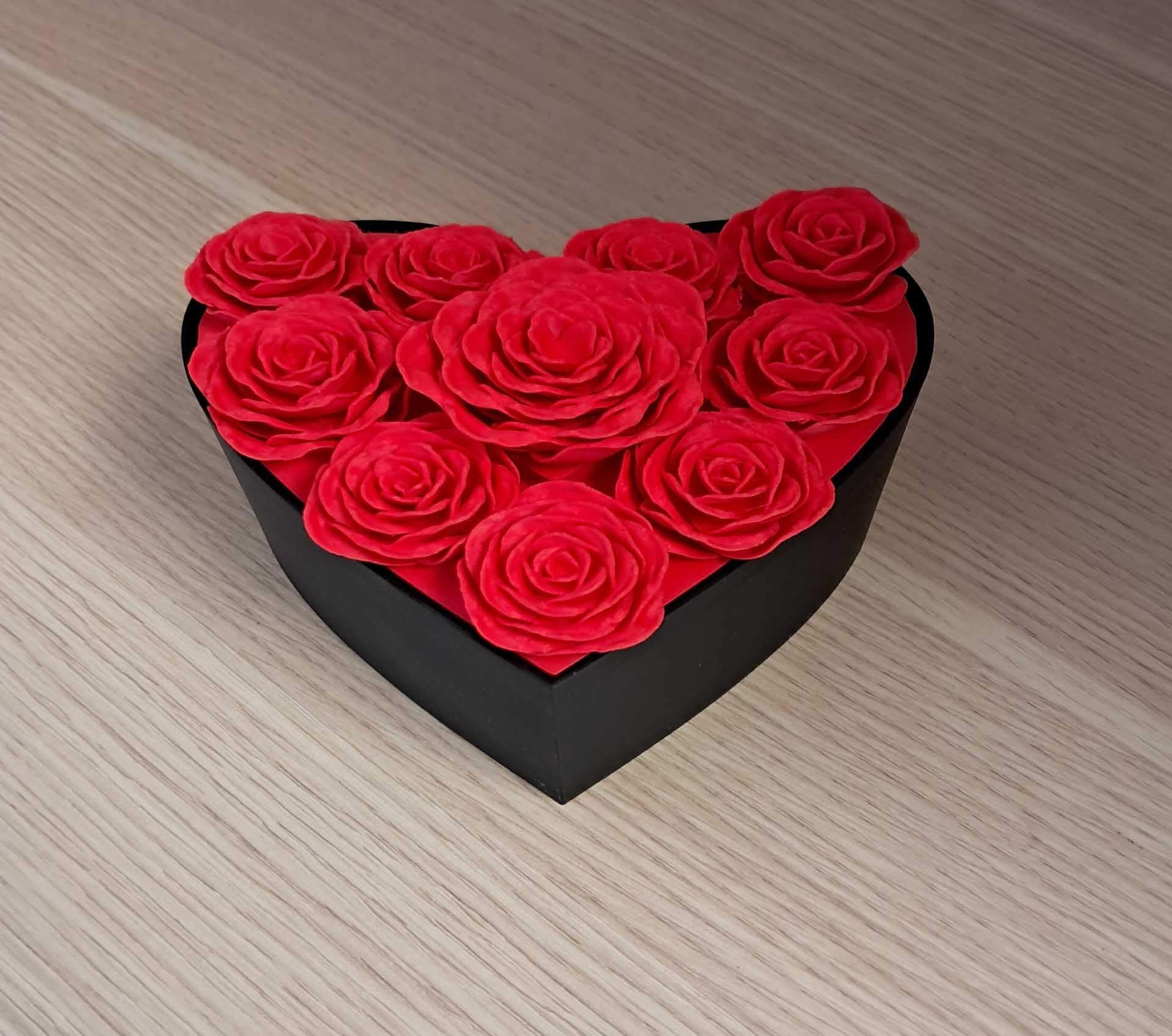 Boîte noire en forme de cœur remplie de roses rouges sur une surface en bois clair