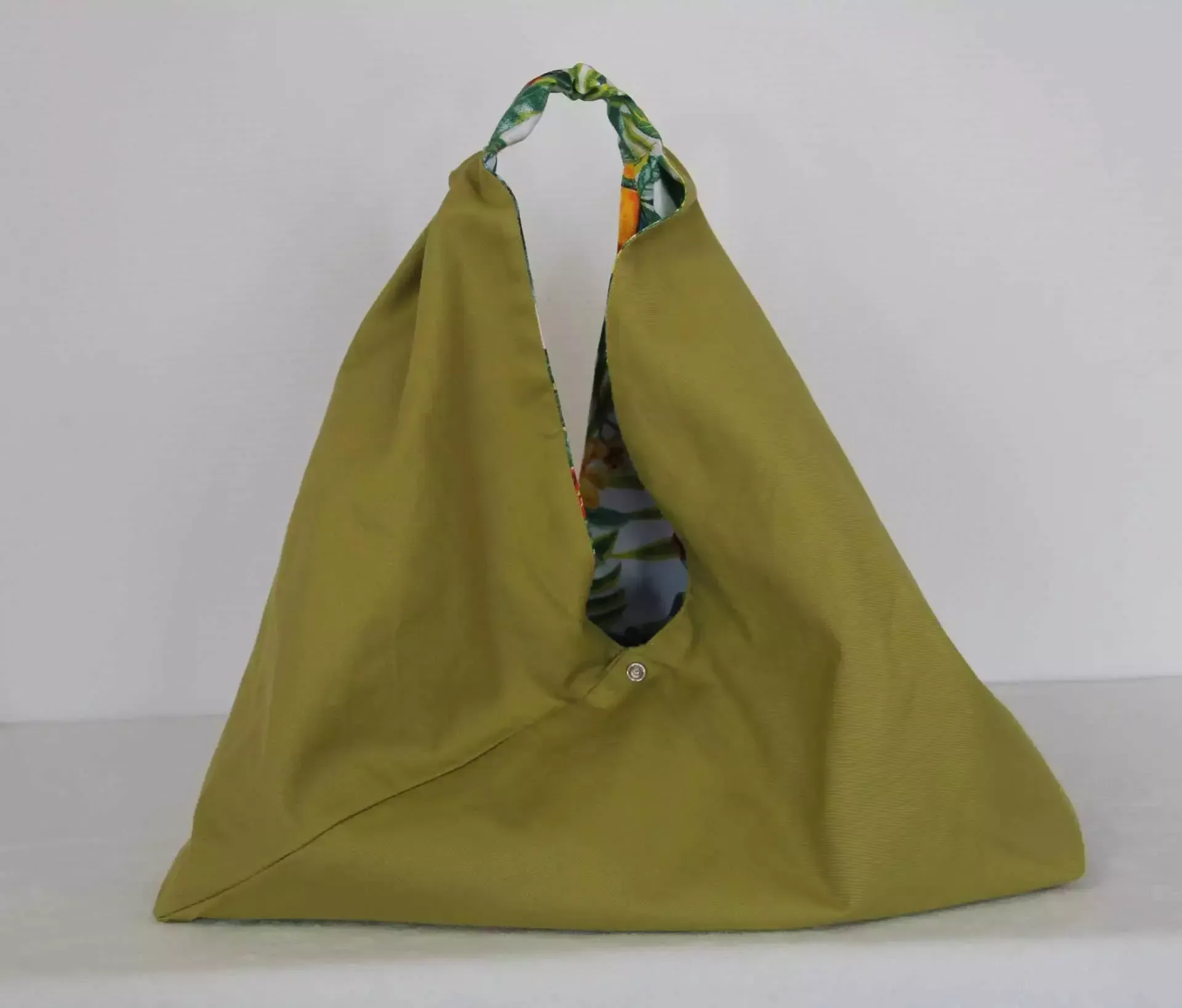 Sac cabas vert olive à anses à motifs, présenté sur fond uni