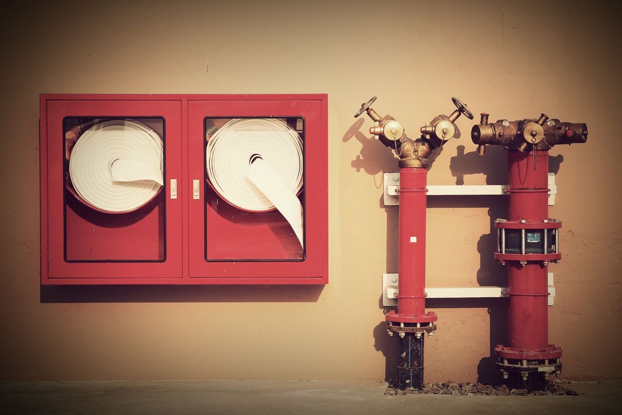 Una boca de incendios de color rojo se encuentra junto a una caja roja en una pared.