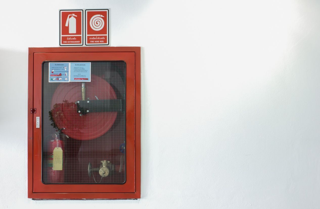 Un extintor rojo está colgado en una pared blanca.
