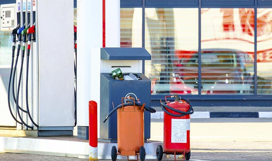 Una gasolinera con dos extintores y un cubo de basura.