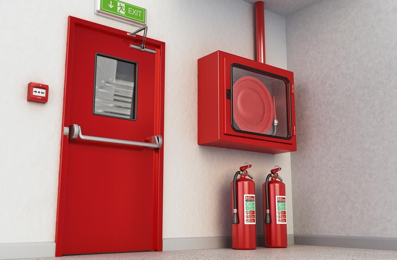 Hay dos extintores rojos junto a una puerta roja.